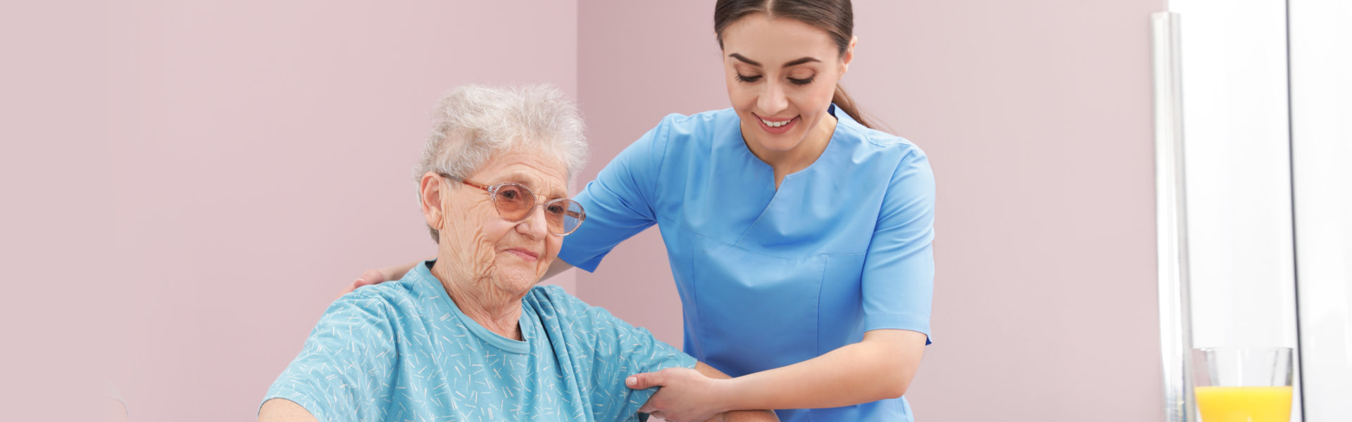 aide assisting an elderly woman in standing up