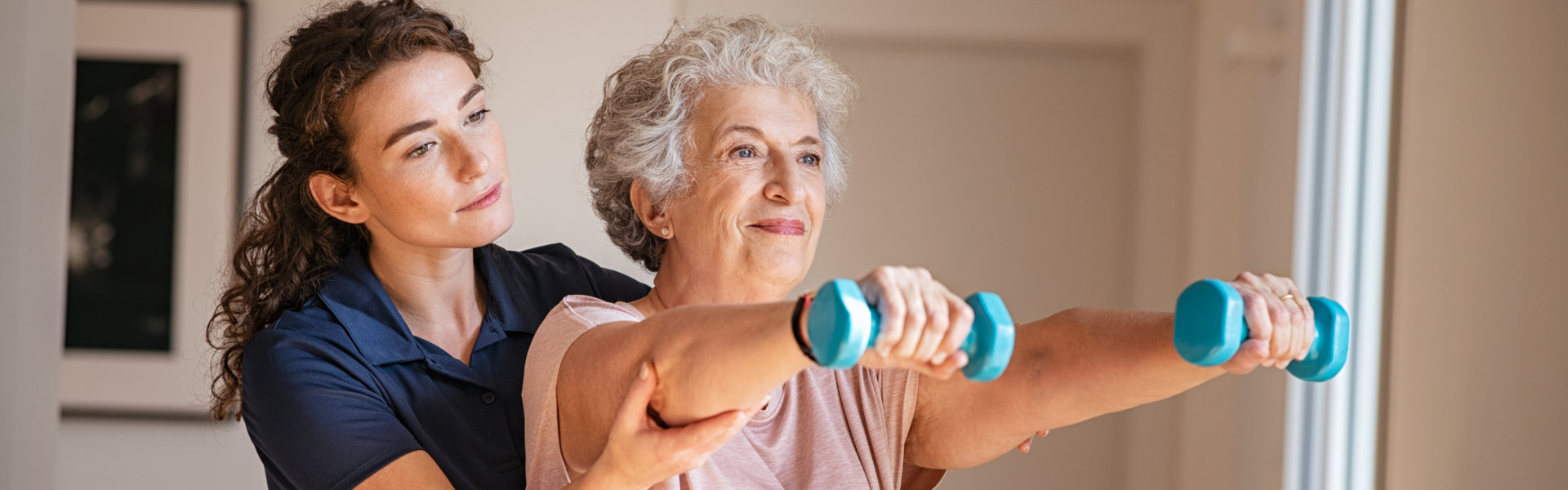 aide assisting an elderly woman in exercising