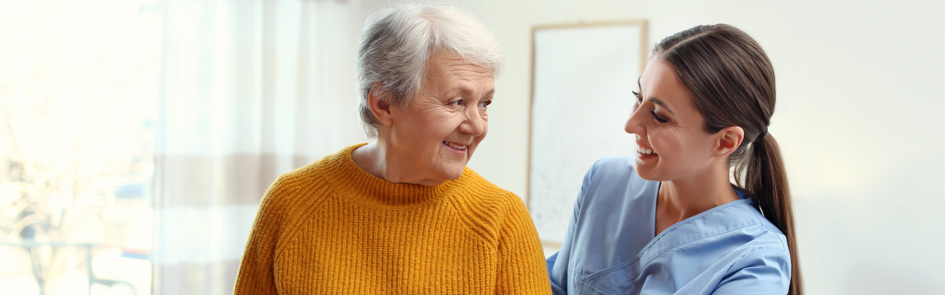 aide and elderly woman smiling at each other